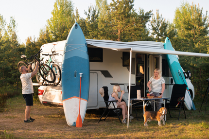 A family near their motorhome with surf boards and bicycles