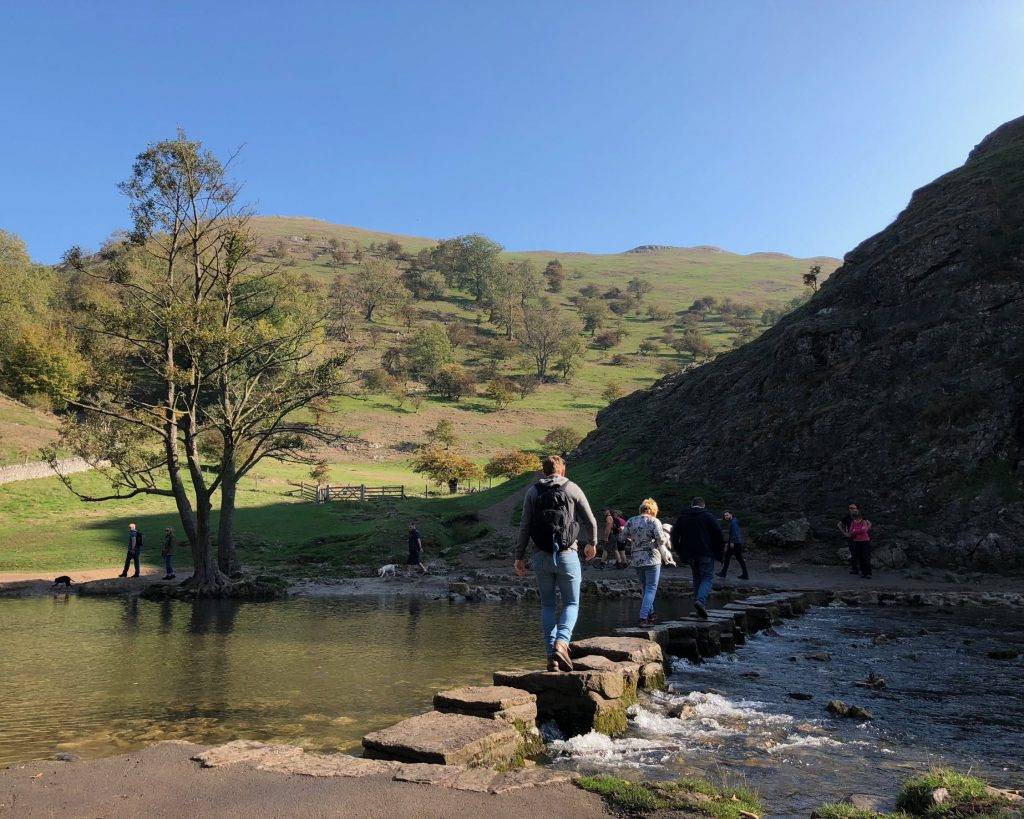 A dad and son crossing a river using stones